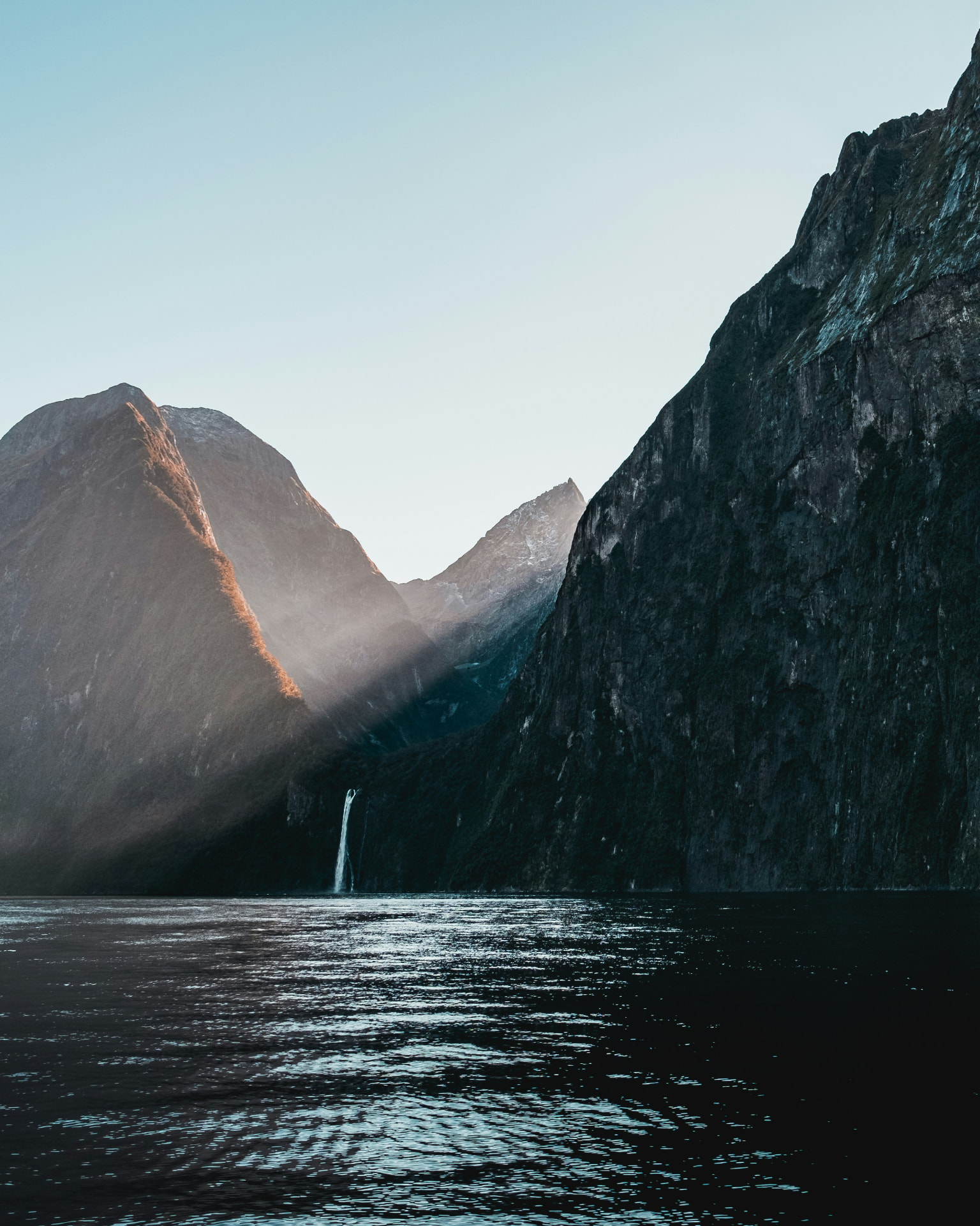 Waterfall and cliffs of Milford Sound fjord at daybreak